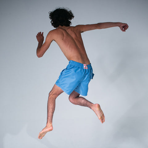 Model jumping up in the air wearing the WHR Short Sky Blue