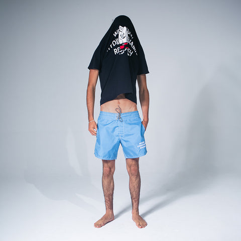 Model wearing Birdie T-Shirt pulled up over head while wearing WHR Shorts in Sky Blue