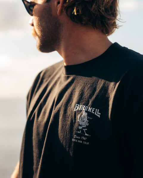 This is close up of Kevin Skvarna, who is wearing the Birdwell 61 t-shirt in white/black that shows Cream colored screenprint shows Birdwell logo with birdie holding up a peace sign with 