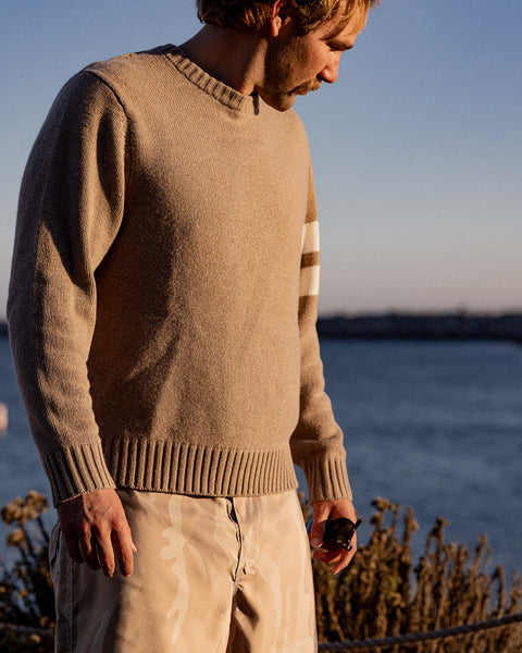 Kevin wearing a bone sweater by a body of water