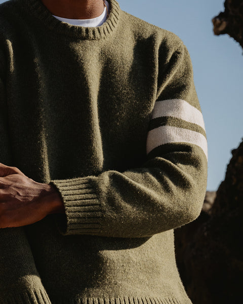 Obi wearing a green comp stripe sweater with white stripes on the sleeves against a natural background
