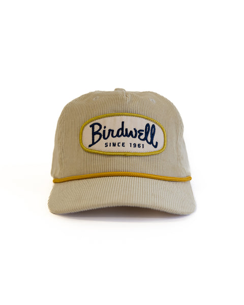 Beige cap with 'Birdwell' logo on a white background