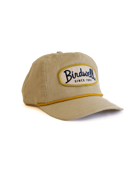 Beige cap with 'Birdwell' logo on a white background