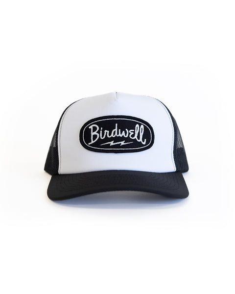 Black and white trucker hat with a Birdwell  logo patch on a white background facing forward. 