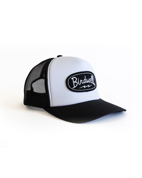 Black and white trucker hat with a Birdwell  logo patch on a white background