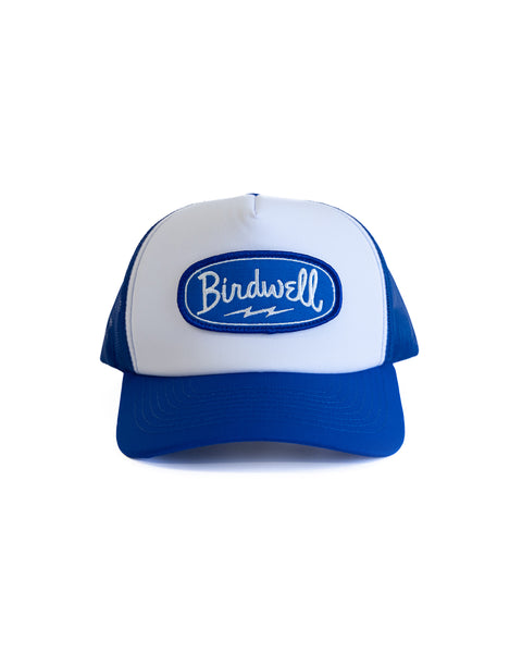 Front of a Blue and white trucker hat with a blue patch with white Birdwell text on a white background