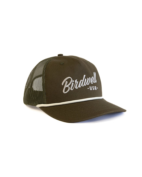 'Birdwell' in white text on olive green hat with a dark olive rim and white string over brim with text on a white background. The hat is facing forward. 