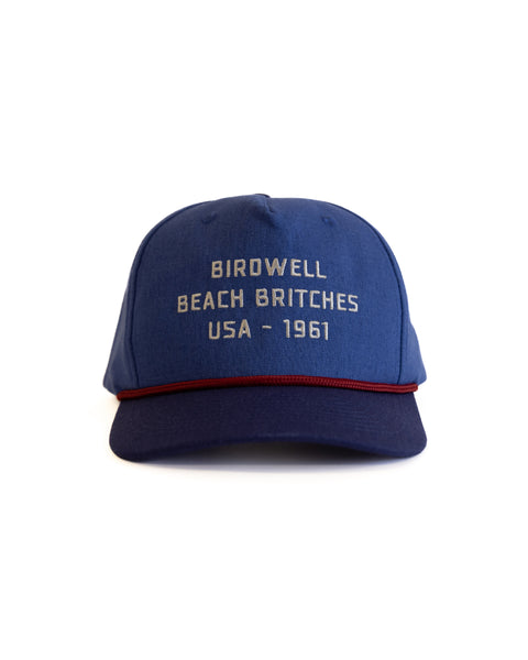 'Birdwell Beach Britches USA - 1961' in white text on blue hat with a dark navy rim and red string over brim with text on a white background facing forward