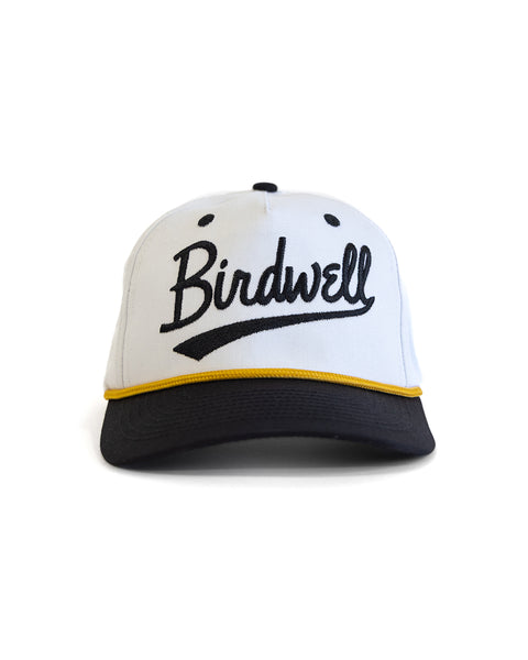 White cap with black brim and yellow trim featuring 'Birdwell' branding on a white background.