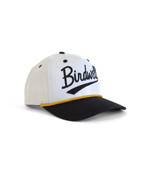 White and black cap with yellow trim featuring 'Birdwell' branding on a white background