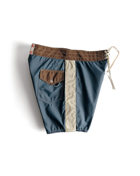 Side view of the 300 Legend Boardshort on white background in tobacco, bone and federal blue. Pocket on left side, two tone with tobacco pocket flap. Drawstring on right side.