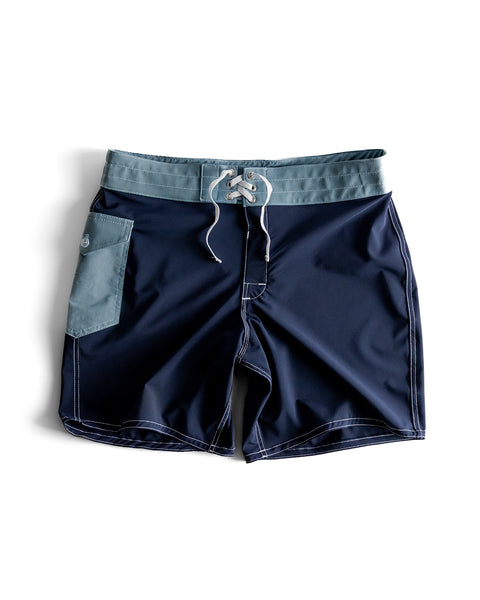 Front view of the 808 boardshorts, navy body with federal blue waistband and pocket. Product on white background.