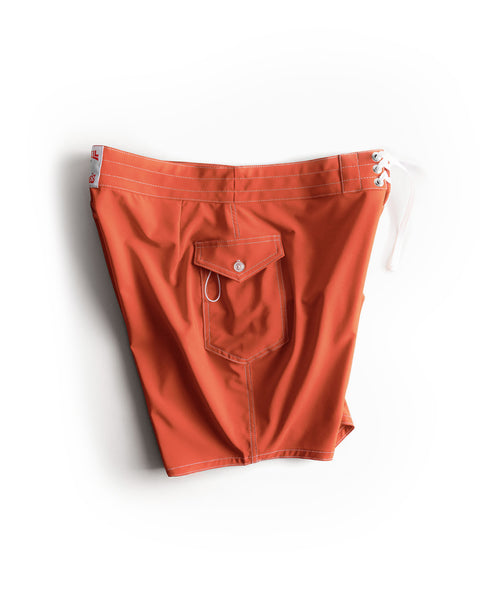 808 SurfStretch® Side Pocket Boardshorts in vibrant Paprika orange, featuring a white drawstring, flap side pocket with button closure, and contrasting white stitching, shown laid flat on a white background. These classic boardshorts are perfect for any summer adventure.