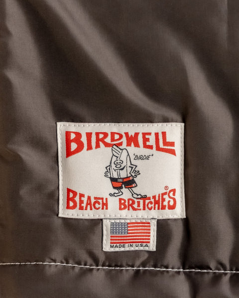 Birdwell Quilted Racing jacket in brown exterior back label that is a white label with Birdie and says Birdwell Beach Britches. It also shows our Birdie character with a made in USA tag on the bottom with the USA flag. 