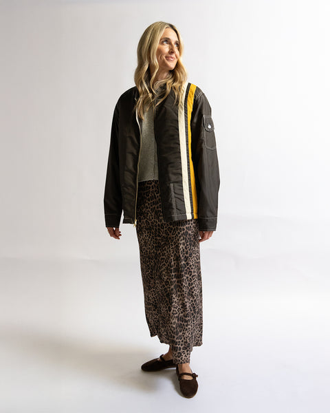 Birdwell Quilted Racing SurfNyl® jacket in brown on a woman model wearing a brown jacket with yellow accents and patterned skirt on a white background
