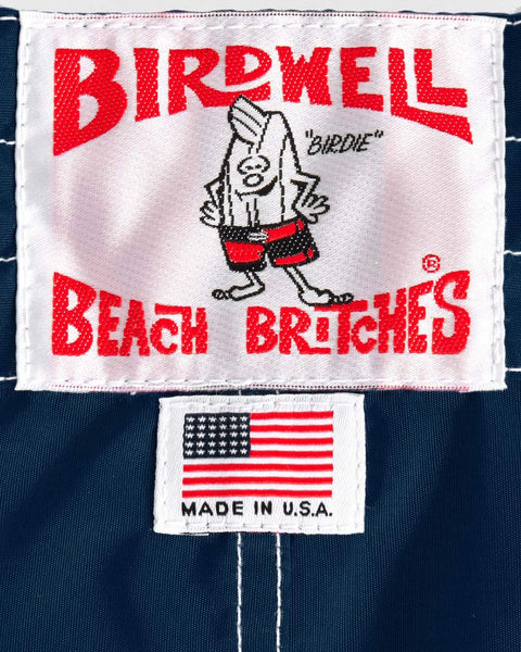 Birdwell Beach Britches label with cartoon character and American flag on a navy background