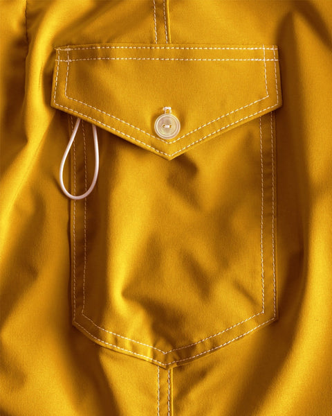 Close-up of a mustard yellow shirt with a pocket and button