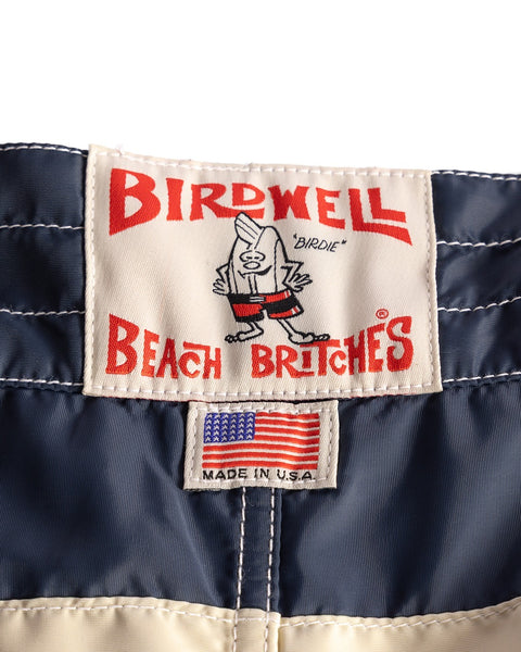 Close-up of a label on a navy blue jacket with 'Birdwell Beach Britches' branding.