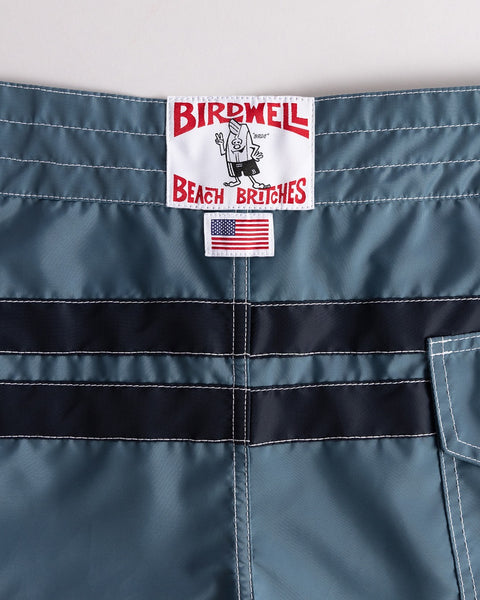 Close-up of a blue garment with a Birdwell label and 'Beach Bitches' text on a gray background