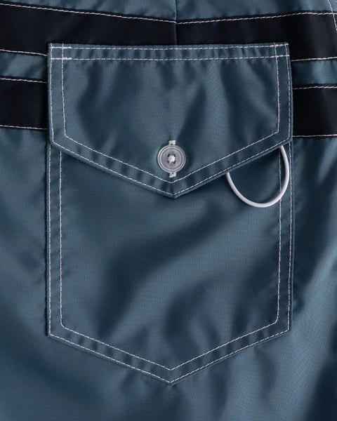 Close-up of a navy blue pocket with a button and ring on a matching fabric background.