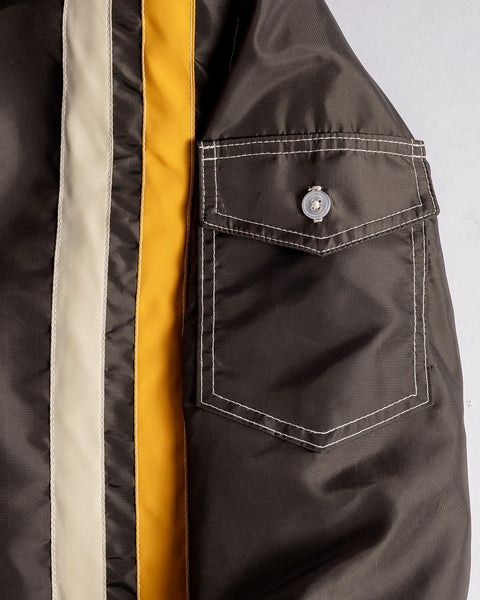 Close-up of the Racing Jacket 26 in Brown/Bone/Gold, featuring white and yellow vertical stripes and a stitched flap pocket with a button closure.