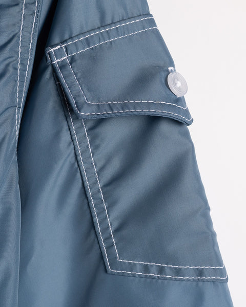 Close-up of the Racing Jacket 26 in Federal Blue/White/Orange, showing a pocket with white stitching and a flap secured by a translucent white button.