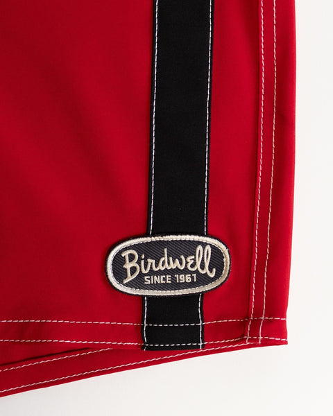 Close-up of the 808 Mono Stripe - Red/Black boardshort featuring white stitching, a black vertical stripe, and an oval 