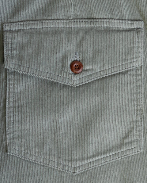 Close-up of a khaki corduroy shirt pocket with flap and button, highlighting stitching and stripes that pair perfectly with the Classic Corduroy Shorts - Eucalyptus, which feature an adjustable drawcord waist.