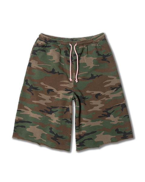 The Baggy Raw Edge Short - Woodland Camo is a pair of knee-length, vintage wash camo shorts with an elastic waistband and a light pink drawstring, shown on a white background.