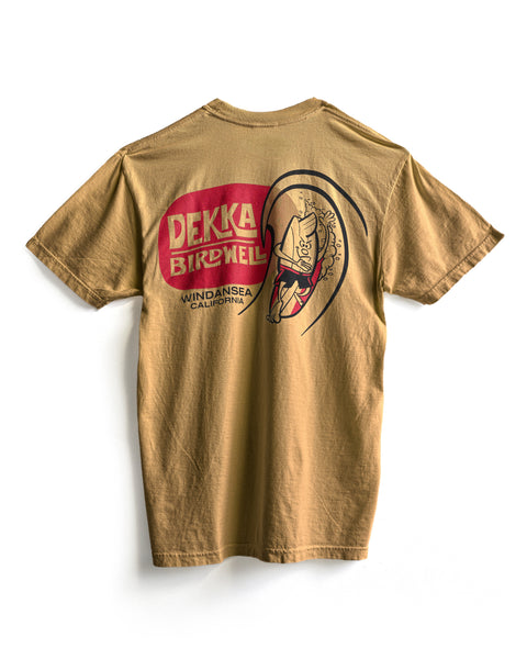 Mustard short-sleeve Birdwell x Dekka T-Shirt made from garment-dyed 100% cotton, featuring a cartoon surfer and “DEKKA BIRDWELL WINDANSEA CALIFORNIA” in bold vintage red and white graphics on the back.