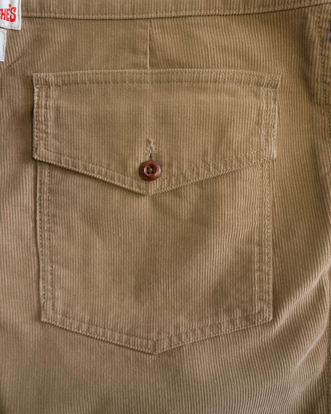 Close-up of a pocket with a flap and centrally placed brown button on the Classic Corduroy Pants - Sand. The texture and stitching details of these 100% cotton corduroy pants, made in Southern California, are clearly visible.
