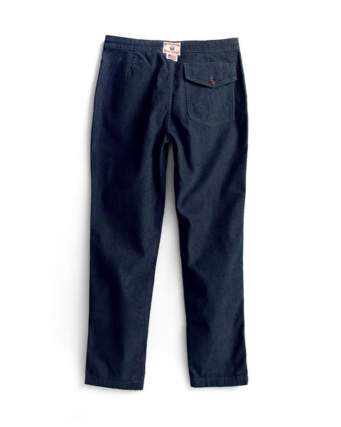 A pair of Classic Corduroy Pants in navy viewed from the back, featuring a single buttoned back pocket and a white tag on the waistband.