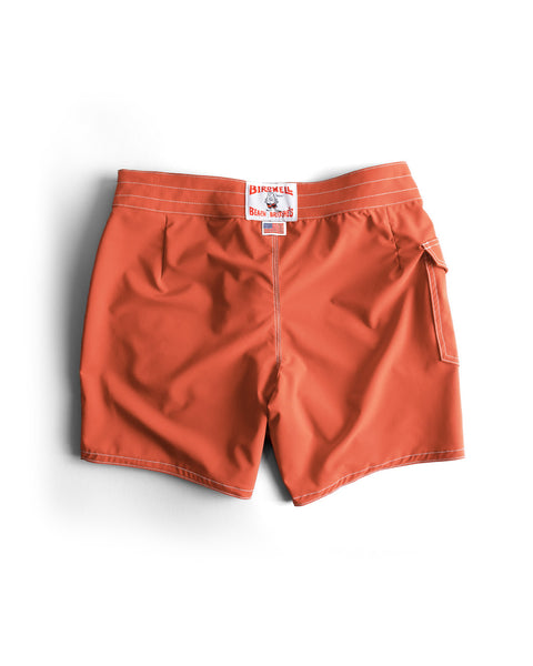 The 806 SurfStretch Side Pocket Boardshorts in Paprika feature bright orange fabric, white stitching, a convenient side pocket, and a red and white Birdwell Beach Britches label on the waistband. Made in the USA, these stretch boardshorts are displayed neatly laid flat against a white background.