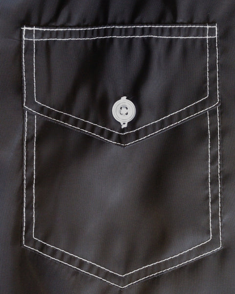 A close-up of the Racing Jacket 26 - Black/White/Red highlights a gray fabric pocket with white stitching and a single gray button at the top center of the flap, capturing the timeless detailing often found on vintage-inspired jackets.