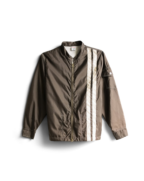 The Racing Jacket 26 - Brown/Bone is an American-made brown bomber jacket featuring a gold zipper, two diagonal bone-colored stripes on the left chest and shoulder, a snap pocket on the left sleeve, and side pockets—displayed against a white background.