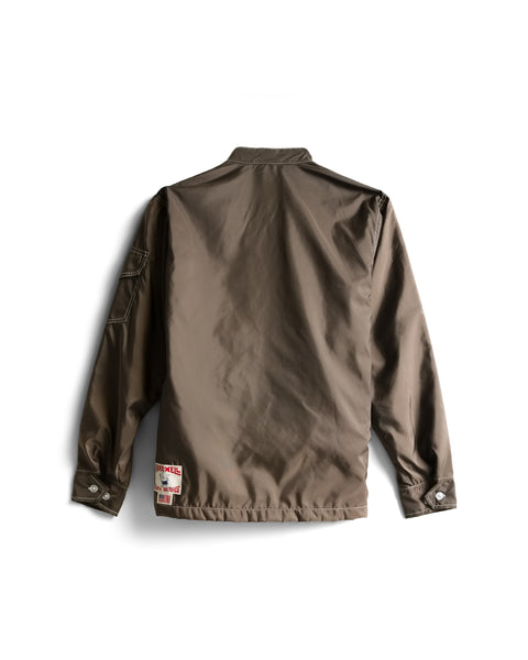 Racing Jacket 26 - Brown/Bone, shown from the back against a white background, features a collar, buttoned cuffs, a sleeve pocket, and a small rectangular patch with text and graphics near the bottom hem. Expertly crafted in America from durable Birdwell SurfNyl fabric, this long-sleeve jacket combines style and resilience.