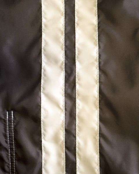 Close-up of durable brown fabric featuring two vertical, parallel bone-colored shiny stripes and a visible stitched seam on the left, showcasing the American-made construction of the Racing Jacket 26 - Brown/Bone.