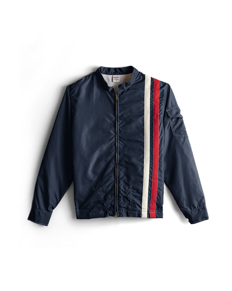 Introducing the Racing Jacket 26 - Navy/Bone/Red, a vintage-inspired American-made jacket featuring a front zipper and two vertical stripes—bone and red—running from shoulder to hem on the left side. This classic piece includes a sleeve pocket and ribbed cuffs, blending timeless style with modern details.
