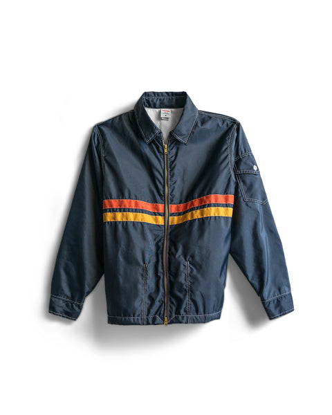 The Comp Jacket 26 - Navy/Gold/Paprika is an expertly American-made jacket in navy, crafted from SurfNyl for lasting durability. It features vibrant orange and yellow (gold and paprika) horizontal stripes across the chest, a zip front, classic collar, and convenient pockets—shown on a white background.