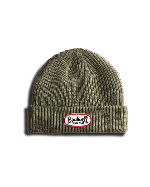 Army green ribbed Potato Watchcap with a cuffed hem and folded brim, featuring an oval Birdwell Since 1961 patch on the front. The background is plain white.