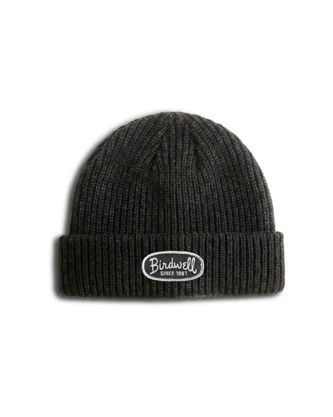 A dark coal-colored Potato Watchcap knit beanie with a folded brim and cuffed hem, featuring an oval Birdwell Since 1961 patch on the front. The ribbed Potato Watchcap beanie is displayed on a white background.
