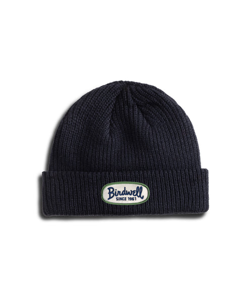 A navy fisherman-style beanie with a cuffed hem and folded brim, featuring a white oval patch that reads Bindwell SINCE 1961 in blue and green text. The Potato Watchcap is photographed on a white background.