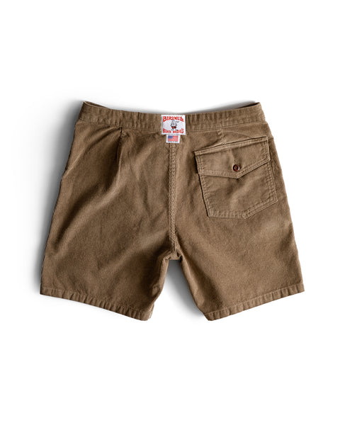 The Classic Corduroy Shorts - Sand are displayed back view and laid flat on a white background. Made from 100% cotton, these shorts feature a single buttoned back pocket on the right side, visible seam detailing, and a red and white brand tag above the waistband.
