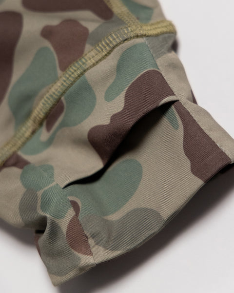 Close-up of a sleeve made from green, brown, and beige camouflage fabric with visible stitching along the hem—this Sunteez Hoodie - Frogskin Camo provides UPF50+ sun protection and is designed to be moisture wicking for extra comfort.