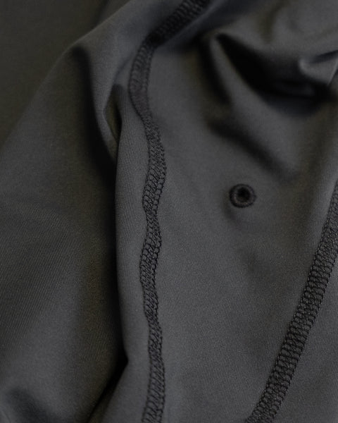 Close-up of black fabric with visible stitching and seams, featuring a single small hole near the center. The texture and folds of the Sunteez Hoodie - Black are highlighted, showcasing detail in the construction and quality UPF50+ materials made in the USA.