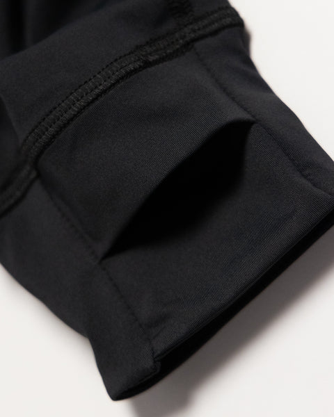Close-up of a black fabric sleeve from the Sunteez Hoodie, featuring visible stitching and a thumb hole, lying on a white surface. This UPF50+ hoodie is made in the USA and designed with moisture-wicking properties for comfort and protection.