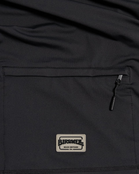 Close-up of the Sunteez Hoodie - Black, featuring a black fabric pocket with a zipper and a rectangular Banks Journal patch that reads BANKS JOURNAL Beach Britches USA. Expertly crafted with attention to detail, this pocket highlights the premium materials commonly found in pieces made in the USA.