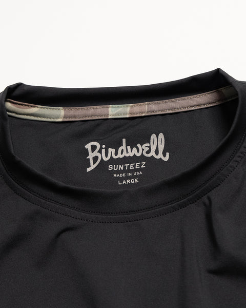 Here’s a rewritten version using your product data: Close-up of the collar on the Sunteez Short Sleeve - Black, featuring the Birdwell Sunteez Made in USA Large print inside. A camouflage lining accents the inside of the collar, showcasing this UPF50+ shirt’s precise craftsmanship and superior sun protection.