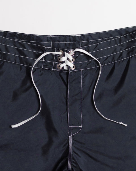 Close-up of the waistband of the 312 Boardshorts - Navy, featuring white stitching and a white lace-up drawstring threaded through silver eyelets. These durable, long-length boardshorts are made in the USA.