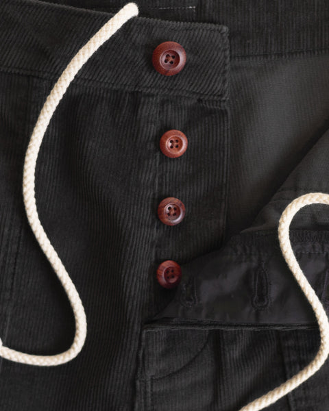 Close-up of the Classic Corduroy Shorts in Charcoal, featuring four brown buttons and a white adjustable drawcord waist. The shorts are partially unbuttoned to reveal black fabric lining, evoking the timeless craftsmanship associated with Birdwell designs.